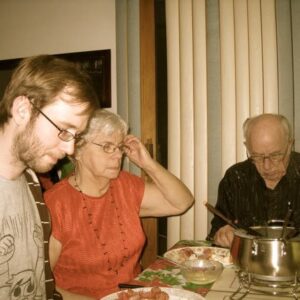 Myself, my granny and papa, at the kitchen table of my childhood home, 2010